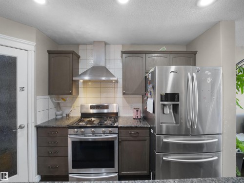 Kitchen featuring a stainless steel gas range, coordinating stainless steel range hood, and a stainless steel French door refrigerator - 1216 29 Avenue Nw, Edmonton, AB - Indoor Photo Showing Kitchen With Stainless Steel Kitchen