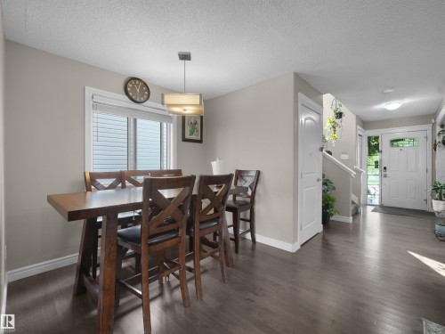 Open concept living area featuring dark wood-finish flooring, a contemporary ceiling light fixture, and a white window frame with horizontal blinds - 1216 29 Avenue Nw, Edmonton, AB - Indoor Photo Showing Dining Room