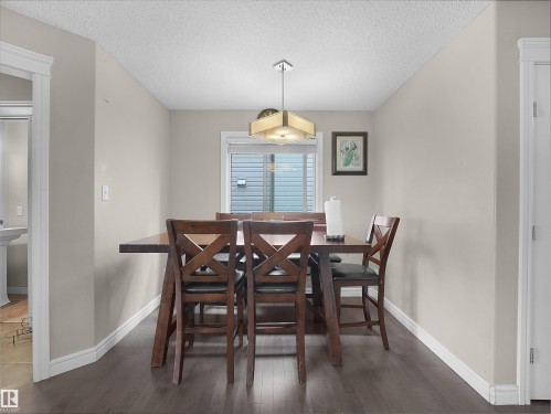 Dining area featuring wood-finish flooring, light neutral wall tones, white trim, and a contemporary ceiling fixture - 1216 29 Avenue Nw, Edmonton, AB - Indoor Photo Showing Dining Room