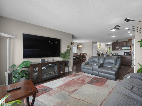 Open-concept living space featuring wood-finish flooring, a built-in media console with an electric fireplace, recessed lighting, and a dining area beyond - 1216 29 Avenue Nw, Edmonton, AB - Indoor Photo Showing Living Room