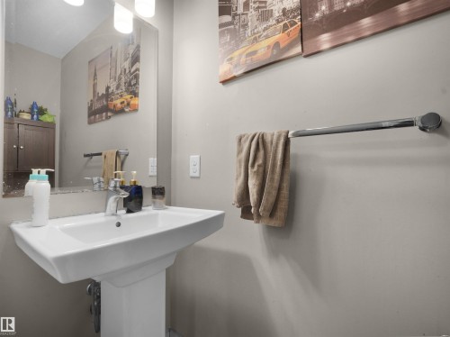 Pedestal sink with chrome faucet, illuminated by a vanity light fixture - 1216 29 Avenue Nw, Edmonton, AB - Indoor Photo Showing Bathroom