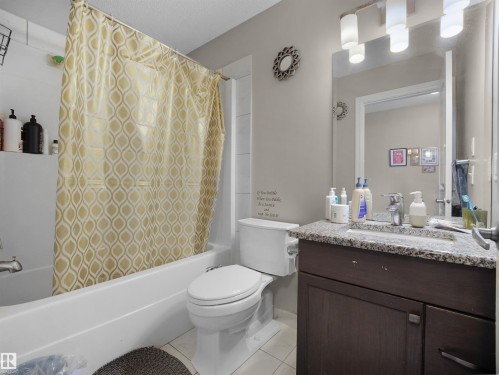 Full bathroom with a white tub-shower combination, dark wood-finish vanity with a stone-finish countertop, and wall-mounted light fixture - 1216 29 Avenue Nw, Edmonton, AB - Indoor Photo Showing Bathroom