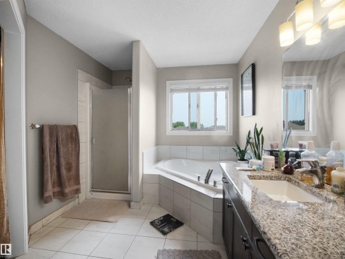 Spacious bathroom featuring a built-in jetted tub, a tiled shower, and a vanity with a drop-in sink and stone countertop - 1216 29 Avenue Nw, Edmonton, AB - Indoor Photo Showing Bathroom