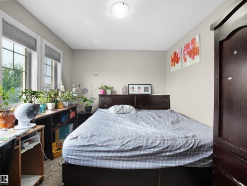 Bedroom featuring two large windows with horizontal blinds, neutral wall paint, and a built-in dark wood headboard - 1216 29 Avenue Nw, Edmonton, AB - Indoor Photo Showing Bedroom