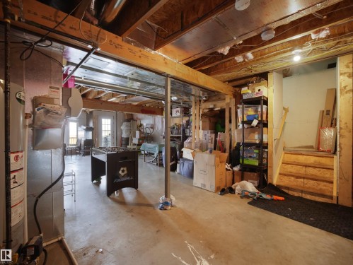 Unfinished lower level featuring exposed ceiling joists, concrete flooring, and a water heater - 1216 29 Avenue Nw, Edmonton, AB - Indoor Photo Showing Basement