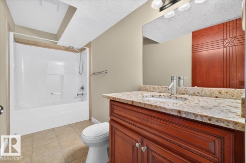 Vanity with a granite-style countertop, undermount sink, and wood-finish cabinetry - #7 10500 103 Av, Morinville, AB 