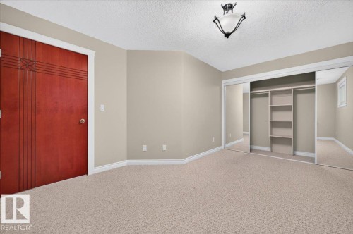Plush carpeting and neutral wall tones complement the decorative wood door - #7 10500 103 Av, Morinville, AB 