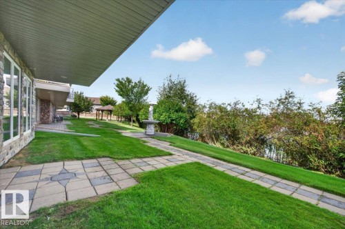 Expansive lawn with stone paver pathways, a decorative fountain, and a gazebo - #7 10500 103 Av, Morinville, AB 