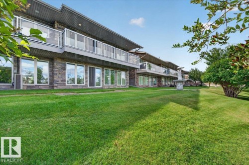 Stone-clad exterior with multiple balconies featuring glass railings - #7 10500 103 Av, Morinville, AB 