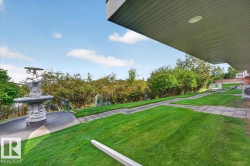 Expansive lawn area with stone paver pathways, mature landscaping, and an ornamental fountain - #7 10500 103 Av, Morinville, AB 