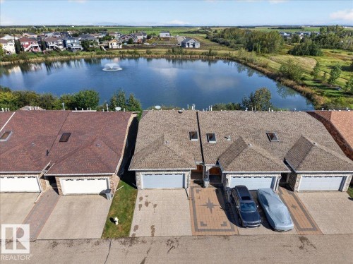 Aerial perspective featuring a residential street with properties backing onto a pond - #7 10500 103 Av, Morinville, AB 