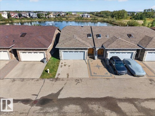Stone facade exterior with integrated garage, skylights, and a patterned paver driveway - #7 10500 103 Av, Morinville, AB 
