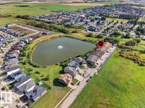 Property situated by a pond with a water feature, featuring a row of townhomes with individual parking spaces - #7 10500 103 Av, Morinville, AB 