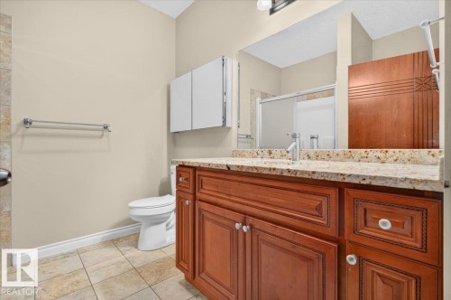 Wood-finish vanity cabinetry with a light-colored countertop, integrated sink, and wall-mounted mirror - #7 10500 103 Av, Morinville, AB 
