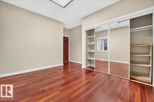 Hardwood flooring, mirrored closet doors, built-in shelving, recessed window, and a brown wood door - #7 10500 103 Av, Morinville, AB 