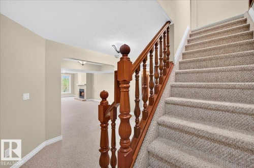 Carpeted staircase with wood banister and balusters - #7 10500 103 Av, Morinville, AB 