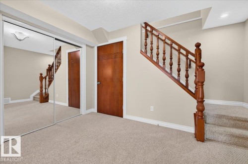 Plush carpeting throughout, mirrored closet doors, rich wood staircase, solid wood doors, and neutral wall tones - #7 10500 103 Av, Morinville, AB 