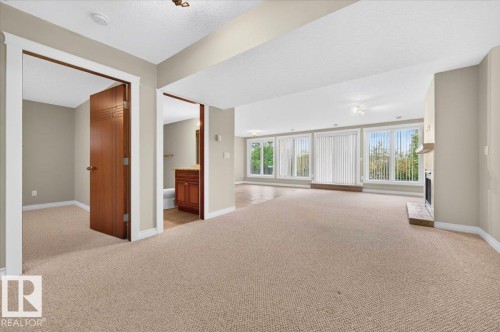 Expansive carpeted area with a fireplace and multiple large windows - #7 10500 103 Av, Morinville, AB 