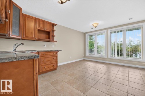Wood-finish cabinetry with a built-in sink, stone-finish countertops, and tile flooring - #7 10500 103 Av, Morinville, AB 