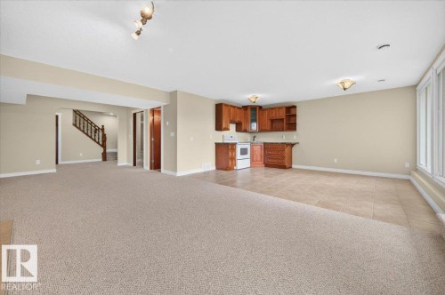 Spacious lower level featuring a full staircase, light-toned carpeting, tiled flooring, built-in cabinetry, and large windows - #7 10500 103 Av, Morinville, AB 