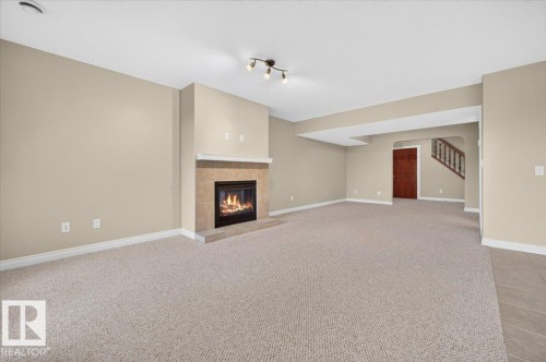 Spacious interior featuring a tiled fireplace with mantel, recessed ceiling lighting, track lighting, and a wood-finish door - #7 10500 103 Av, Morinville, AB 