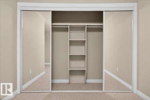 Built-in closet with mirrored sliding doors, integrated shelving, and hanging rods - #7 10500 103 Av, Morinville, AB 