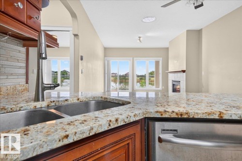 Kitchen featuring granite countertops, stainless steel double basin sink with a high-arc faucet, and integrated dishwasher - #7 10500 103 Av, Morinville, AB 