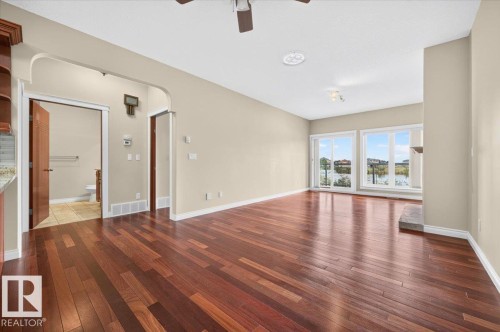 Hardwood flooring throughout, a stone fireplace hearth, and multiple windows with an outward opening glass door - #7 10500 103 Av, Morinville, AB 