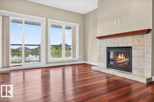 Hardwood flooring, tiled fireplace with wood mantel, and sliding glass patio doors - #7 10500 103 Av, Morinville, AB 