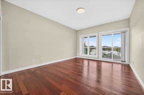 Hardwood flooring, painted walls, ceiling-mounted light fixture, sliding glass door, and large window - #7 10500 103 Av, Morinville, AB 