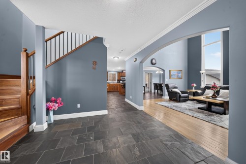 Slate-finish tile flooring, hardwood flooring, an arched entryway, a double-height window, and a wood staircase with metal balusters - 6904 18 Avenue Sw, Edmonton, AB 