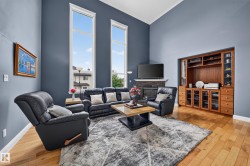 Vaulted ceiling with tall windows, built-in entertainment center, stone-clad fireplace, and wood-finish flooring - 