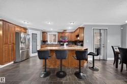 Slate tile flooring, recessed lighting, wood cabinetry, built-in stainless steel appliances, and a kitchen island with seating - 