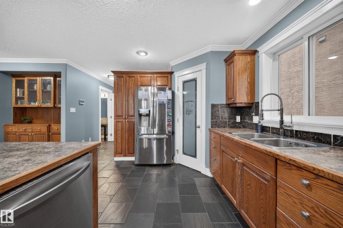 Slate tile flooring, recessed lighting, wood cabinetry, stainless steel appliances, and a double basin sink with a gooseneck faucet - 6904 18 Avenue Sw, Edmonton, AB 