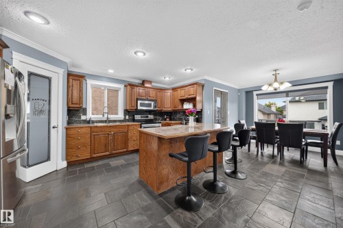 Expansive kitchen and dining area featuring stone tile flooring, wooden cabinetry, and recessed lighting - 6904 18 Avenue Sw, Edmonton, AB 