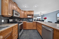 Wood-finish cabinetry, stainless steel appliances, dark stone-finish countertops, black tile backsplash, and slate-finish flooring - 