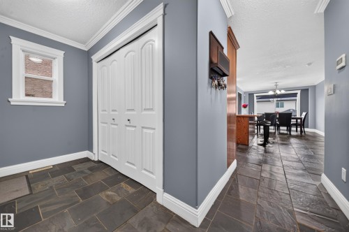 Slate tile flooring, white bi-fold closet door, white window trim, and crown molding - 6904 18 Avenue Sw, Edmonton, AB 