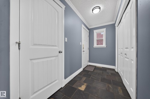 Slate tile flooring, white trim, white paneled doors, white bi-fold closet doors, and recessed lighting - 6904 18 Avenue Sw, Edmonton, AB 