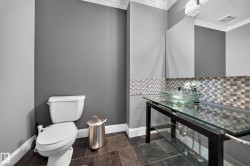 Modern powder room featuring a glass vessel sink, mosaic tile backsplash, slate-style flooring, and crown molding - 