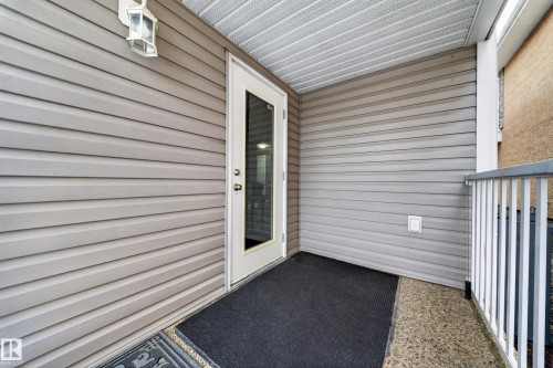 Covered entrance with horizontal siding, a glass-paneled door, and a white outdoor lantern - 6904 18 Avenue Sw, Edmonton, AB 