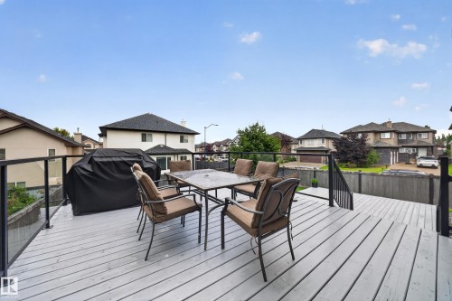 Expansive outdoor deck featuring wood-finish flooring and black metal railing with glass panels - 6904 18 Avenue Sw, Edmonton, AB 