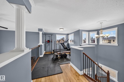 Wood-finish flooring, white crown molding, decorative columns, bay windows, and a chandelier with a ceiling medallion - 6904 18 Avenue Sw, Edmonton, AB 