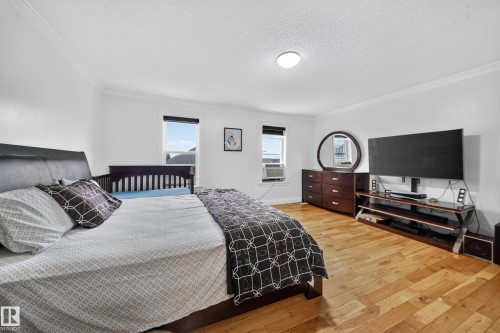 Hardwood flooring, white walls, crown molding, two windows with blinds, and a flush mount ceiling light - 6904 18 Avenue Sw, Edmonton, AB 