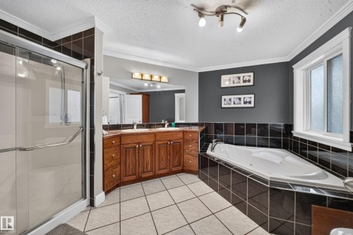 Built-in corner soaking tub, glass-enclosed shower, dual vanity with wood-finish cabinetry, and tiled flooring - 6904 18 Avenue Sw, Edmonton, AB 