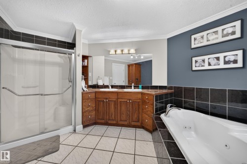 Spacious bathroom featuring a dual vanity with wood-finish cabinetry, a separate shower enclosure, a soaking tub, and tile flooring - 6904 18 Avenue Sw, Edmonton, AB 