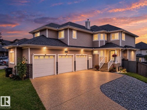 Exterior siding with stone accents, three-car garage, covered entry porch, bay windows, and a concrete driveway - 6904 18 Avenue Sw, Edmonton, AB 