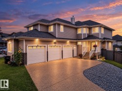 Exterior siding with stone accents, three-car garage, covered entry porch, bay windows, and a concrete driveway - 