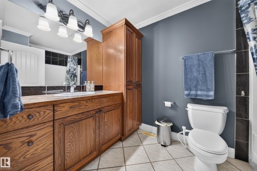Wood-finish vanity with an integrated sink and countertop, complemented by a tall storage cabinet - 6904 18 Avenue Sw, Edmonton, AB 
