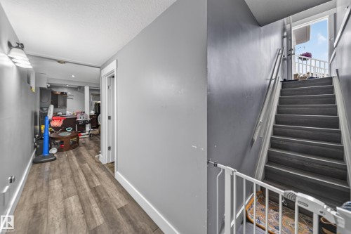 Wood-finish flooring throughout, white trim, and a staircase with a white handrail - 6904 18 Avenue Sw, Edmonton, AB 