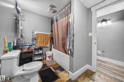 Bathroom featuring a built-in tub and shower combination, a toilet, and multi-toned tile flooring - 